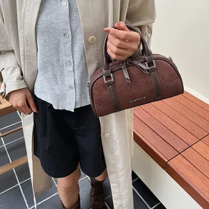 Bolso Boston marrón oscuro con textura mate y asas dobles combinado con gabardina beige
