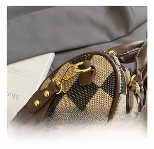Detailed close-up of golden metal hooks and hardware on a checkerboard handbag