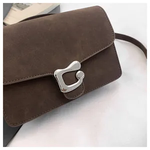 Detalle del bolso de hombro en ante marrón café con hebilla metálica plateada