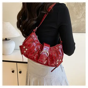 Detalle de bolso rojo efecto cocodrilo con hebilla plateada y remaches metálicos