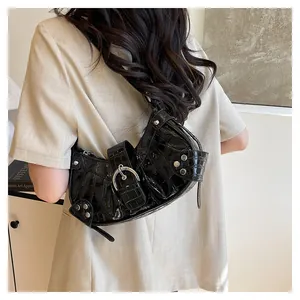 Detalle de bolso de hombro negro con textura de cocodrilo y hebillas plateadas en modelo