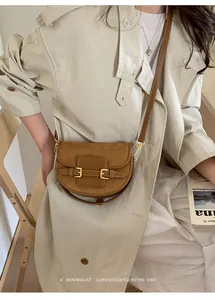 Detalle de bolso de ante marrón combinado con una gabardina beige de estilo retro
