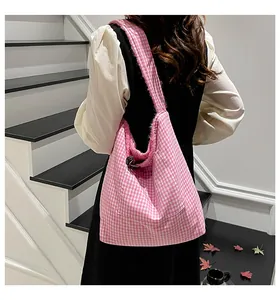 Detalle del bolso tote de cuadros rosa y blanco con correa de flecos y bolsillo frontal