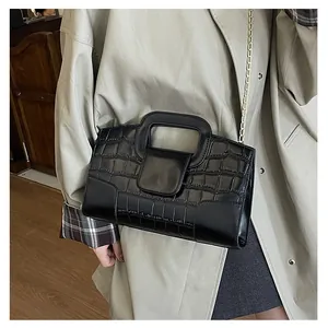 Detail of black faux-crocodile leather tote bag with gold chain and cutout handle
