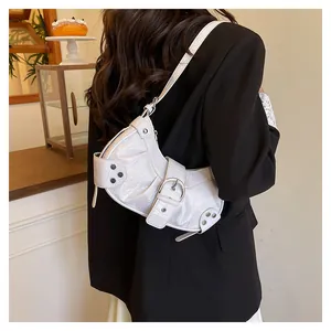 Detalle de bolso de hombro blanco con relieve de cocodrilo, hebilla y tachuelas