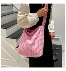 Detalle de bolso tote de tela de cuadros rosas con bordes desgastados y bolsillo frontal