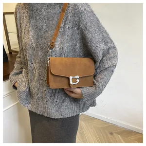 Bolso de hombro en gamuza mate marrón con una hebilla metálica en forma de C plateada