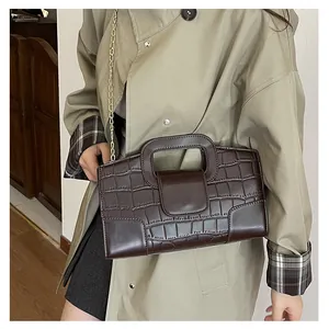 Detalle del bolso marrón oscuro con grabado de cocodrilo y elegante cadena dorada