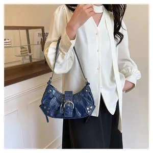 Detalle del bolso de hombro azul oscuro con grabado de cocodrilo y hebillas plateadas