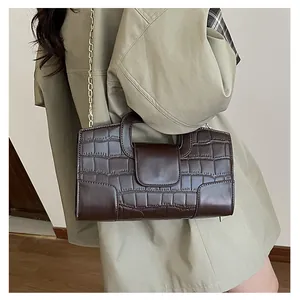 Detail of dark brown faux-crocodile leather tote bag with gold chain and cutout handle