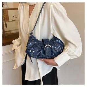Detalle del bolso de hombro azul oscuro con motivo de cocodrilo y hebilla plateada