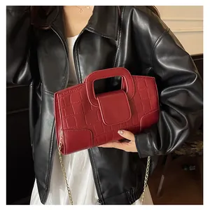 Detalle de textura de cocodrilo rojo y asa cuadrada calada en el bolso de cuero