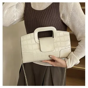 Detalle del bolso tote crema con textura de cocodrilo y cadena metálica dorada