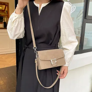 Bolso de hombro caqui mate con hebilla plateada llevado por una modelo en un entorno urbano
