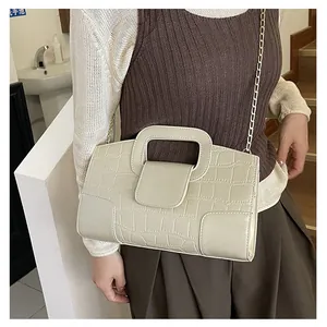 Detalle de la textura de cocodrilo beige en el bolso con elegante cadena dorada metálica
