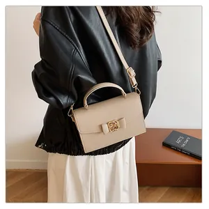 Sac à main beige texture litchi avec nœud, porté en bandoulière pour un style élégant