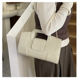Detalle de textura de piedra y cadena dorada en el bolso de hombro blanco crema