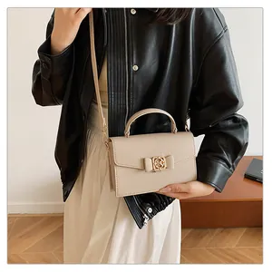 Détail du sac à main en cuir beige avec nœud décoratif et fermoir pivotant en métal doré