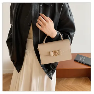Gros plan d'un sac à main beige avec nœud et fermoir doré porté par un mannequin