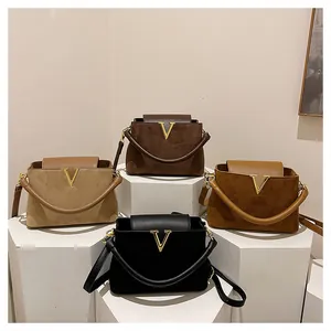 Detalle de bolsos bandolera de ante en cuatro colores con hebillas metálicas en forma de V