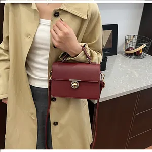 Détail du sac en cuir bordeaux à grain avec fermoir rotatif doré et bandoulière fine