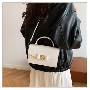 Détail d'un sac à main beige structuré avec nœud en cuir et fermoir doré chic