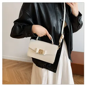 Détail du sac à bandoulière en cuir blanc avec nœud et boucle dorée sur le mannequin