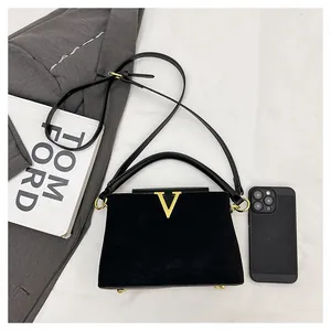 Primer plano de un bolso vintage de ante negro con una hebilla metálica dorada en forma de V