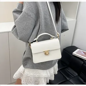 Détail d'un sac à main blanc à texture litchi et fermoir doré porté par un mannequin
