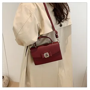 Gros plan sur un sac en cuir grainé bordeaux avec nœud et boucle dorée élégante