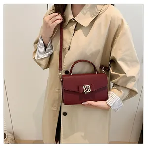 Détail du sac à main bordeaux en cuir grainé avec nœud et boucle en métal doré
