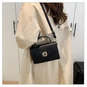 Mannequin portant un sac à main noir grainé avec boucle dorée et trench-coat beige