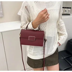 Détail du sac à main bordeaux en cuir litchi avec une boucle rectangulaire dorée chic