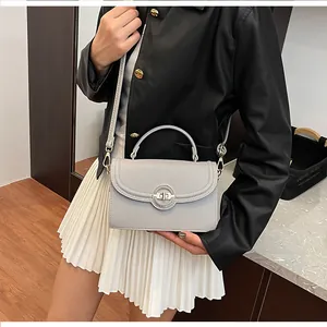 Détail d'un sac à main gris grainé avec fermoir argenté et bandoulière tissée