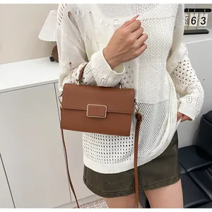 Détail du sac en cuir grainé caramel avec boucle dorée porté par un mannequin