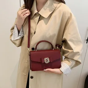 Sac à main bordeaux à nœud avec texture litchi porté par un mannequin en manteau beige
