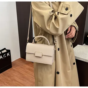 Sac à main beige texture litchi porté avec un trench-coat au style minimaliste