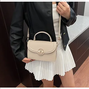 Détail du sac à main crème avec texture litchi et fermoir métallique rond chic