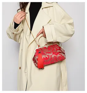 Détail du sac en soie rouge brodée d'or avec poignée en métal et pampille rouge élégante