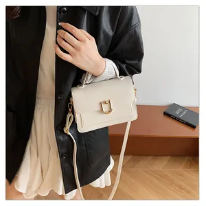 Détail du sac à main beige en cuir grainé avec boucle dorée en forme de U élégante