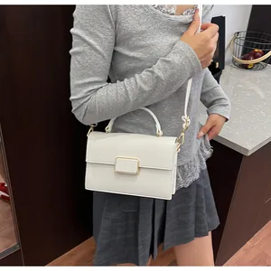 Détail du sac à main en cuir grainé blanc avec boucle dorée et bandoulière élégante