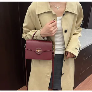 Détail du sac à main en cuir grainé bordeaux avec fermoir rotatif en métal sur le mannequin