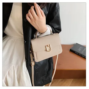 Détail du sac à main beige texture litchi avec boucle dorée en U et bandoulière amovible