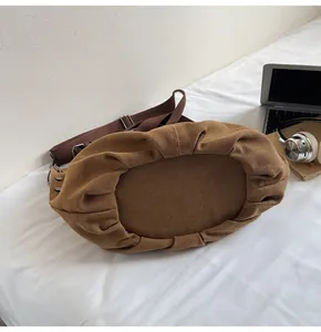 Detalle del bolso tote vintage de lona con pliegues texturizados y hebilla de metal