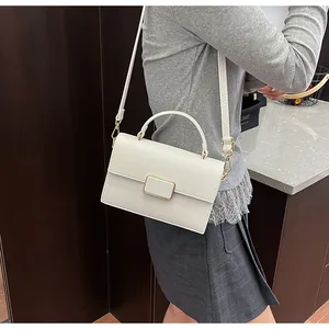 Détail du sac à main blanc à motif litchi avec fermoir en métal doré et bandoulière chic