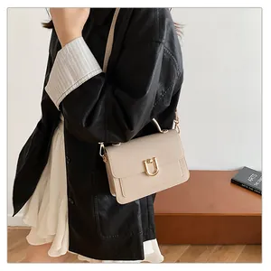 Détail d'un sac bandoulière beige en cuir grainé avec boucle fer à cheval dorée