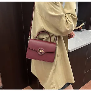 Détail du sac en cuir bordeaux à motif litchi avec boucle dorée sur un mannequin