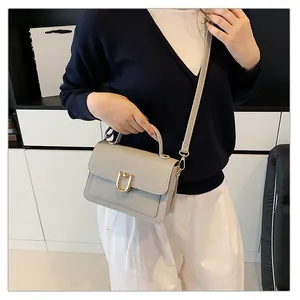Gros plan détaillé du sac à main en cuir grainé avec boucle en U dorée et bandoulière