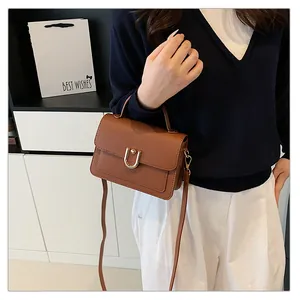 Détail d'un sac à main marron grainé avec fermoir en métal doré en forme de U