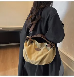 Bolso tote hobo de lona con asas de cuero marrón llevado por modelo con abrigo negro